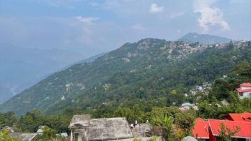 Scenic view of Kalimpong town nestled in the green Himalayan foothills, a key destination in a Peer Baba tour package.